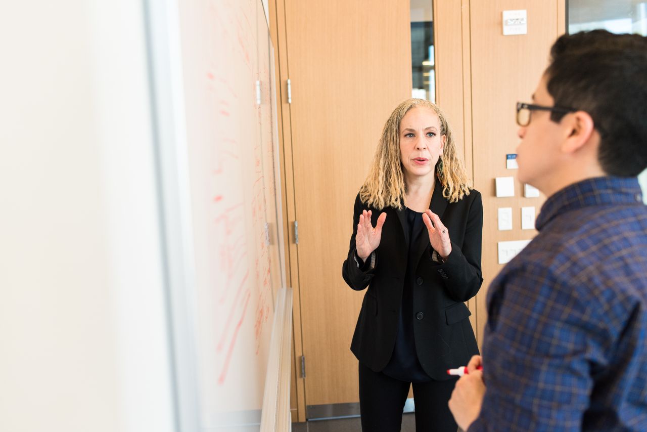 Two professionals discussing ideas at a workplace whiteboard. Collaborative team meeting.